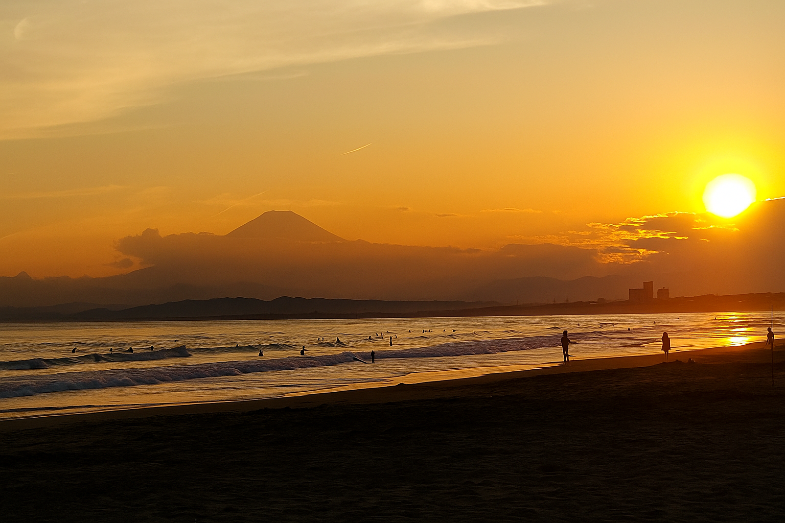 鵠沼海岸の夕暮れ時、波間に浮かぶサーファーと遠くに浮かぶ富士山